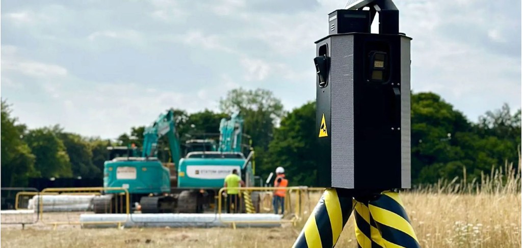 Autarke Überwachungssäule auf temporärer Baustelle, Bagger und Absperrungen im Hintergrund