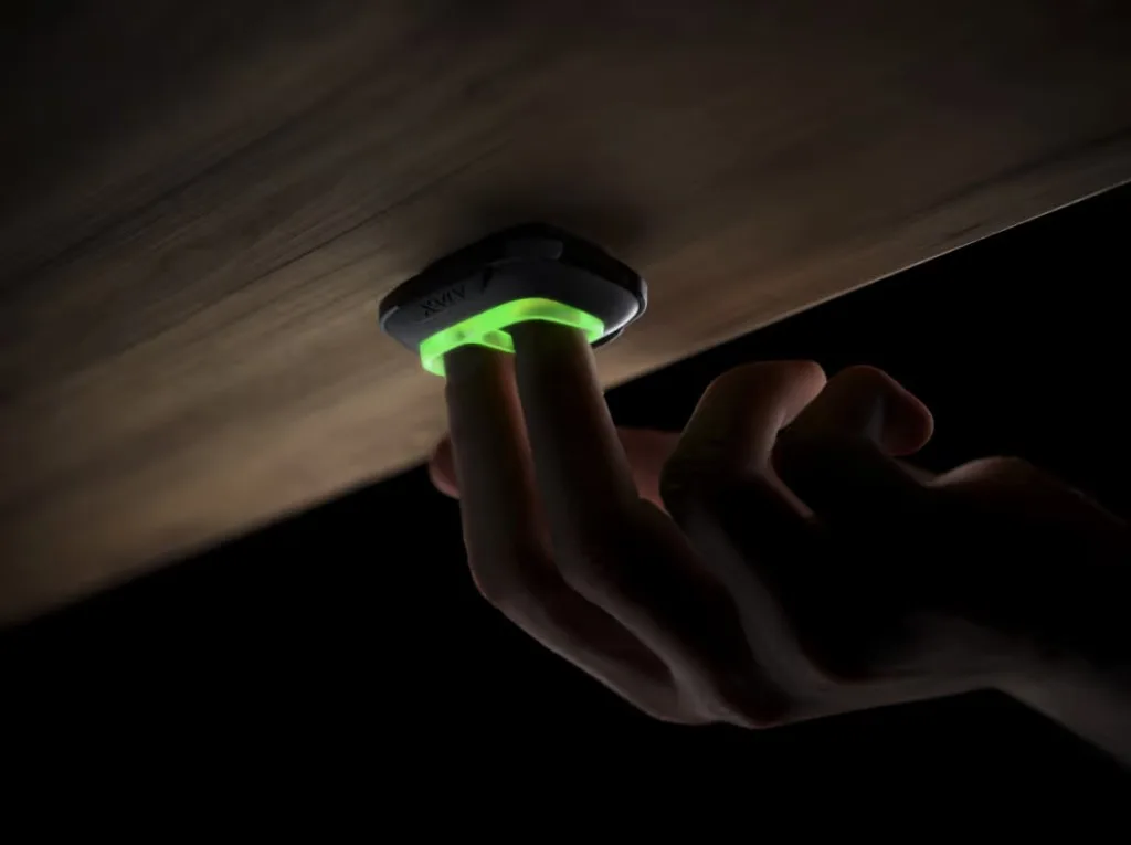 Staff member discreetly triggering an Ajax DoubleButton under a desk