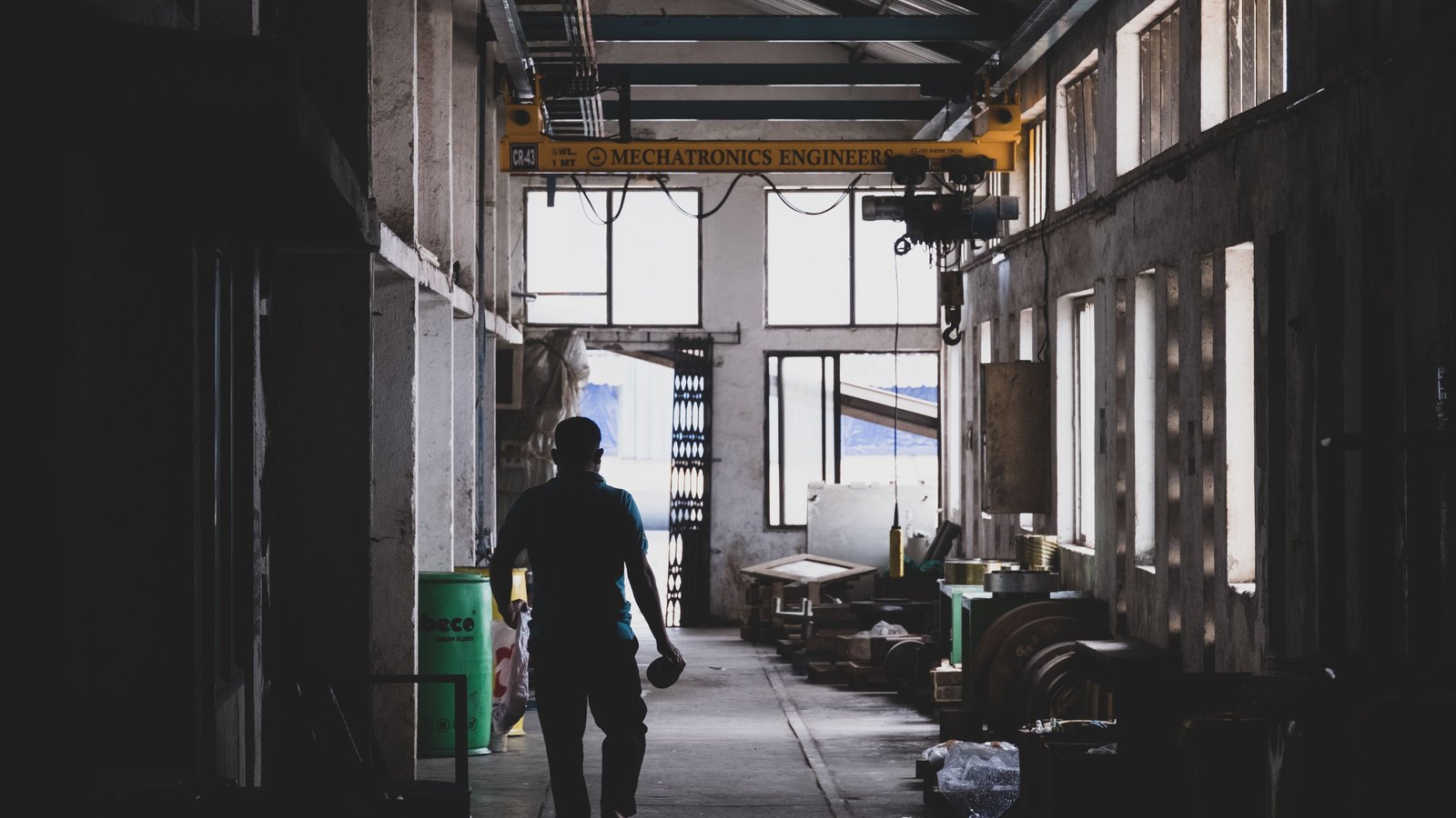 Person geht durch eine dunkle Industriehalle